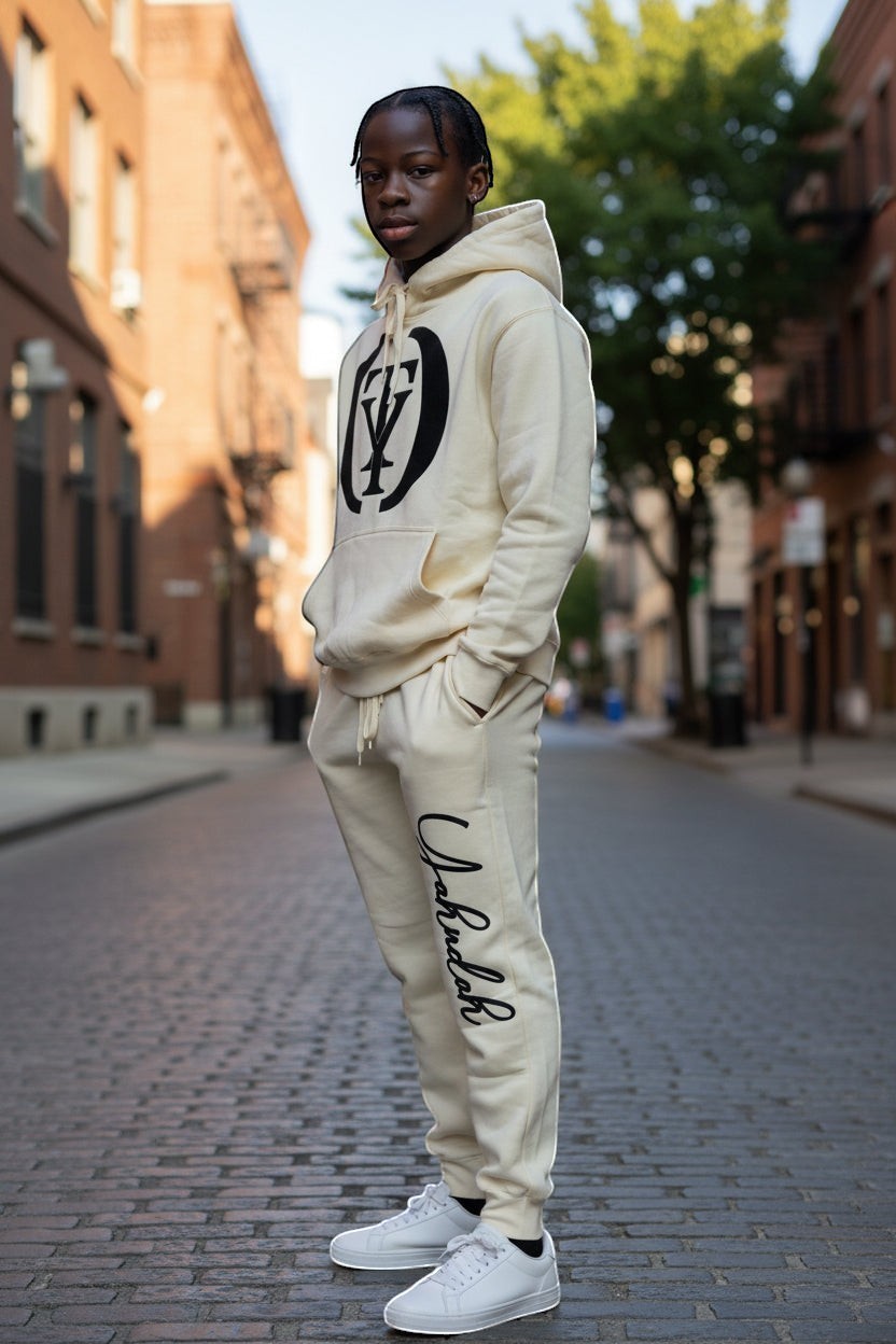 YAHUDAH COLLECTION cream fleece jogger sweatpants set with hoodie and embroidered logo. Model wearing white sneakers.